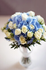 A beautiful bouquet of white and blue roses in a vase on the table.
