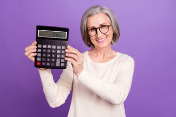Photo of pensioner woman grey hair hold calculator tool using for accountant numbers cash budget isolated over violet color background