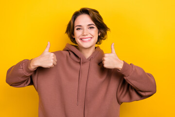 Photo of charming woman lady raise thumbs up approve good quality agree wear brown hood shirt isolated yellow color background