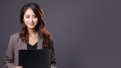 Smiling Asian businesswoman holding laptop computer