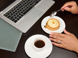 Close-up. Overhead view of a female hand holding a tea spoon over a French dessert with lemon...
