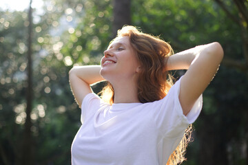 Portrait of happy young woman breathing deep fresh air in the summer forest or park at summer sunny day