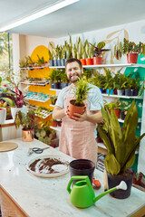 portrait happy entrepreuneur owner holding a houseplant in plant store