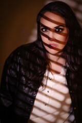 Beautiful photo os a young pretty woman effectfully lit through venetian blinds