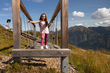 Smiling girl in pink deftly moves on suspended logs to train balance