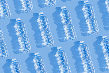 Minimal Pattern Plastic bottles water at sunlight with shadow on blue, aesthetic top view. Distilled drinking water. Pollution, environmental protection. Eco trend to reduce disposable plastics