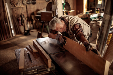 Senior male carpenter measuring wood in a carpentry shop