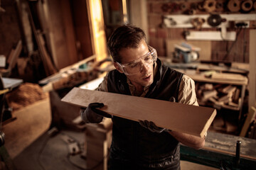 Young male carpenter measuring wood in a carpentry shop