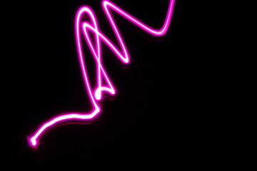 Luz en forma de viboreo color rosa de luz de neón, con  velocidad y movimiento vibratorio borroso,  presenta un diseño abstracto original con fondo negro - obrazy, fototapety, plakaty