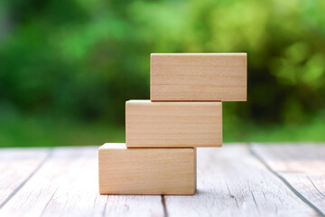 3 stacking rectangle empty wooden blocks on table with green natural blur background for own customer text or letters. Idea of environment, energy or business concept. Front view, banner copy space.