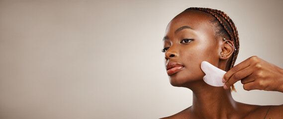 Skincare, black woman or gua sha on face for beauty, acne or blood circulation in studio on brown...