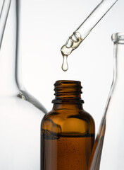 Close up of dropping face serum with bottle on white background.