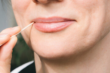 A beautiful woman holds a toothpick in her mouth. Oral hygiene. Healthy concept.