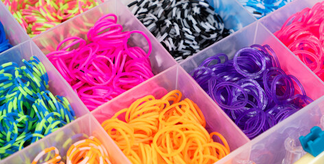 A set of multi-colored elastic bands for weaving bracelets for children.