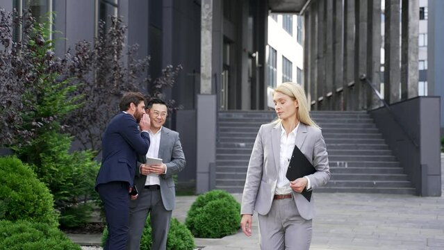 Coworkers employees group man Whispering Behind Back. men mock colleagues are gossiping at background behind young specialist worker workmate bullying or sexism problem at work place in office outside