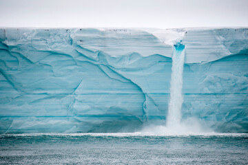 Meltwater pours over an ice cliff from the surface of the Nordaustlandet ice cap; Svalbard, Norway