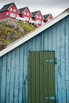 Padlocked door in a shack overlooked by housing on a ridge; Sisimiut, Greenland
