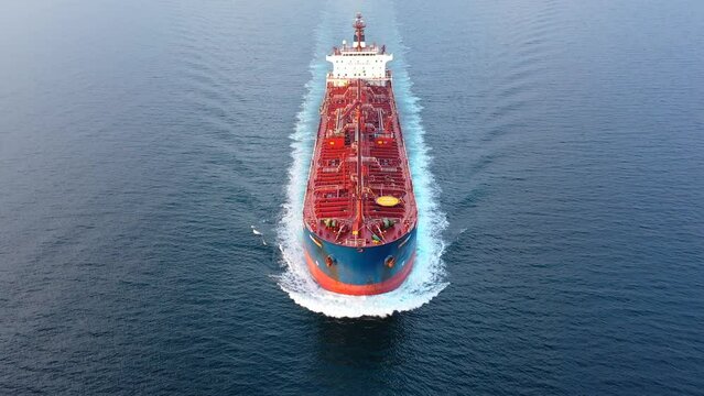 Flying over a crude oil tanker underway in open sea. Bow, forecastle, red upper deck, pipe lines, winches, wheelhouse, upper running bridge, radar mast of a supertanker ship on ride. Aerial, close up
