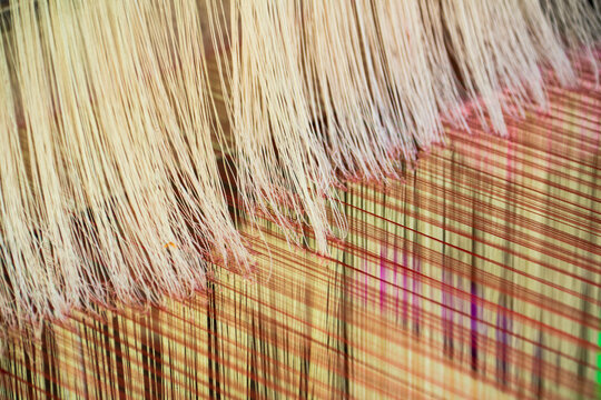 Strands of fine yarn in the process of creating fabric on a loom at Ock Pop Tock, the living craft center; Luang Prabang, Laos