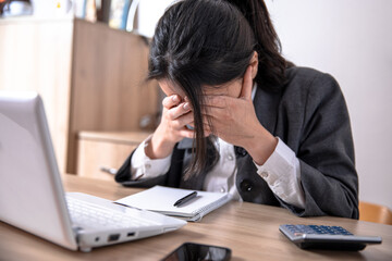 Tired worker holding his head at his desk