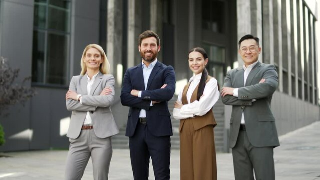 Portrait of a team of business people man and woman in formal suits looking at camera smiling. Group of successful confident employees co-workers near office building work space. outside outdoors