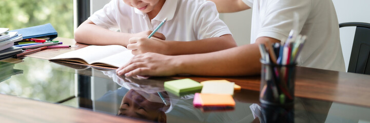 Father helping his son doing homework and studying education at home with happiness family moment