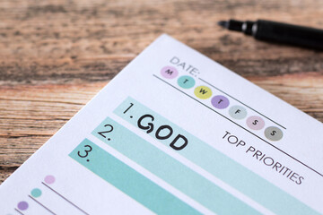 God first, Christian top priority list handwritten in notebook on wooden table. Close-up. Christian...