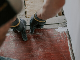 A young man removes old linoleum from the floor.