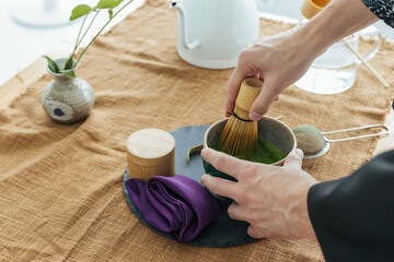 Traditional Japanese green tea match close-up. Matcha tea ceremony, a bamboo Chassen whisk for...