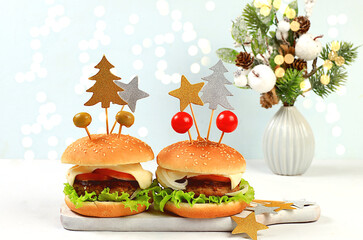Christmas New Year's dishes, festive burgers with tomatoes, olives, meat and salad on a festive table with a live Christmas tree and decorations, New Year's food. Advertising banner for cafe or store,