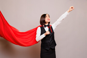Asian waitress wearing superwoman cloak raising clenched fist and looking upwards. Catering service...