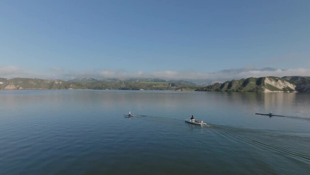 Aerial panoramic footage of large water surface and high cliffs in background. Rowing on lake. Cachuma Lake, California, USA