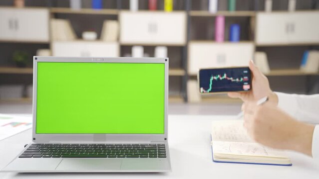Stock market chart and laptop with green screen.