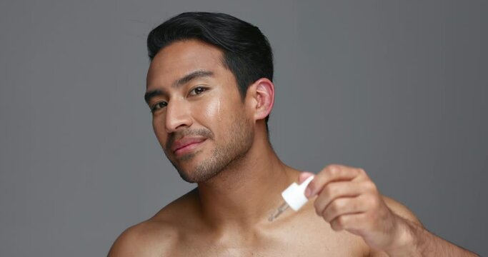 Man, face and essential oil for beauty, skincare and cosmetics product on a gray, studio background. Young asian person in portrait with facial serum, dermatology dropper or collagen for skin care