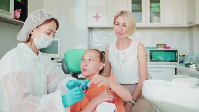 Teen girl and her mother on orthodontic appointment with orthodontist.