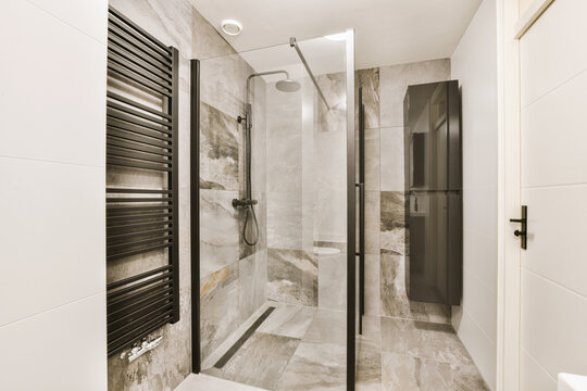 Shower cabin and marble walls and white tiles in bathroom