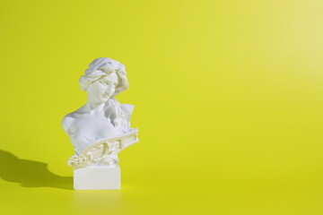 Marble head of young woman on yellow background, copy space