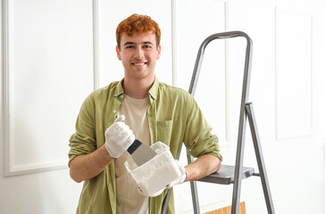 Young man with putty knife and plaster working at home