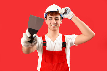 Male decorator with putty knife on red background