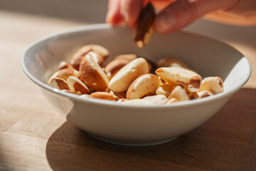 Brazil nuts.hand takes brazil nuts from a plate.Healthy fats.Brazil nuts in the diet.Nuts and seeds. healthy snack.