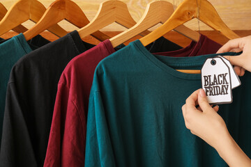 Female hands with stylish t-shirts and sale tag, closeup. Black Friday