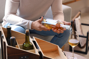 Young man with bottle of wine at home, closeup