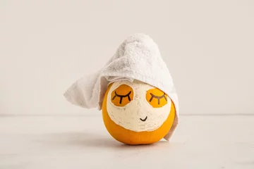 Abwaschbare Fototapete Spa Pumpkin with drawn face, mask and towel on light background