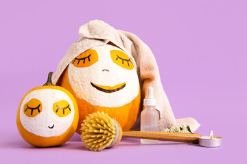 Pumpkins with masks and spa supplies on lilac background