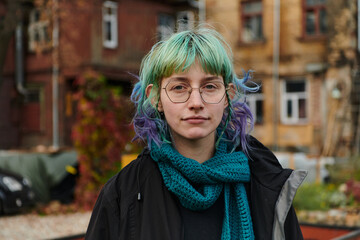 A captivating portrait of a young, interesting girl with striking blue hair, taken in the park in...