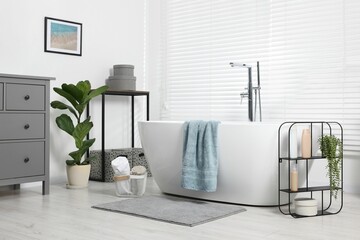 Stylish bathroom interior with bath tub, houseplants and soft light grey mat - obrazy, fototapety, plakaty