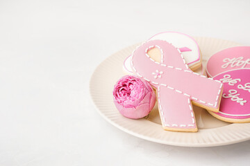 Plate with pink cookies and rose flower on white grunge background. Breast cancer awareness concept