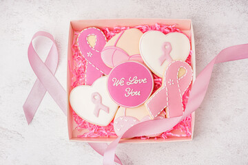 Box with pink cookies and ribbon on white grunge background. Breast cancer awareness concept