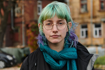 A captivating portrait of a young, interesting girl with striking blue hair, taken in the park in front of her house, showcasing her charismatic and stylish personality against a natural outdoor