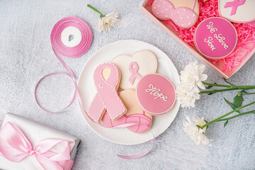 Plate with pink cookies in shape of ribbon on grey grunge background. Breast cancer awareness concept